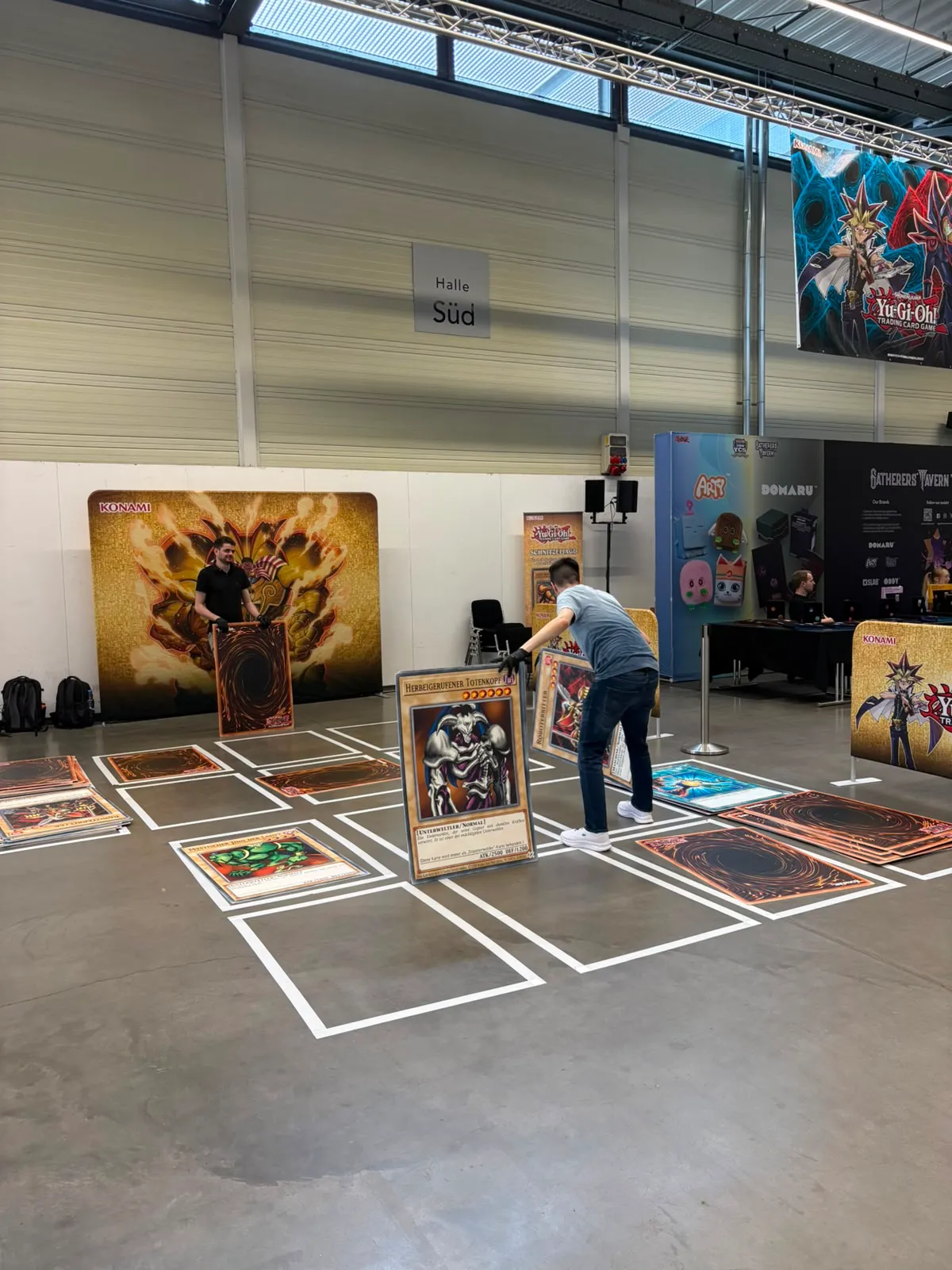 Aktionsfläche mit großem Yu-Gi-Oh!-Spielfeld und übergroßen Karten in der Messehalle